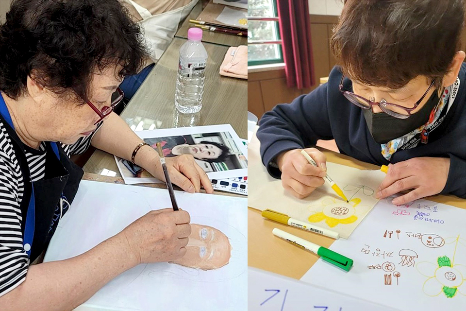 미술교실 참여자로, 중년 여성 두 명이 각자 물감과 싸인펜으로 종이에 그림을 그리고 있다. 