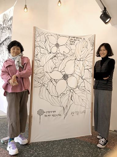 김진주 작가와 창파 아트디렉터가 산딸나무 그림 양쪽에 서서 포즈를 취하고 있다.