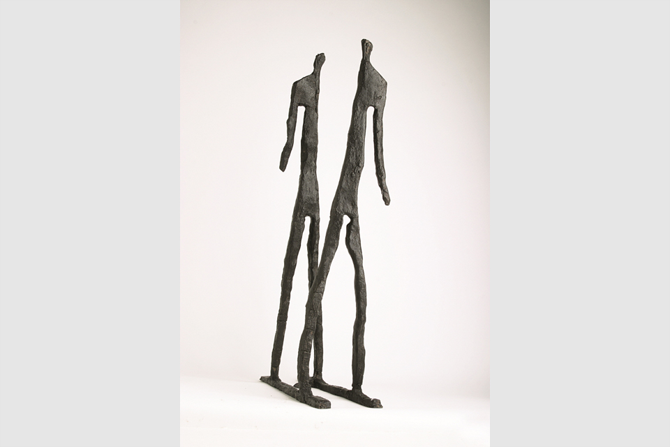앙상한 뼈대 모양의 두 사람 청동 조각이 앞뒤로 서 있다. 앞사람은 왼팔만, 뒷사람은 오른팔만 있다.
