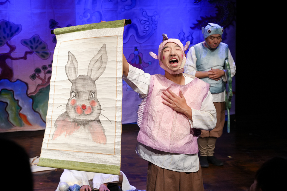 한 배우가 토끼가 그려진 그림을 활짝 펼쳐보이고 있다.