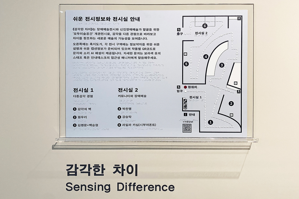 아크릴판에 A4 용지에 프린트된 안내문이 붙어 있다. 안내문에는 ‘쉬운 전시정보와 전시실 안내’ 설명문과 함께 한글과 점자를 표기한 전시공간 도면이 그려져 있다.