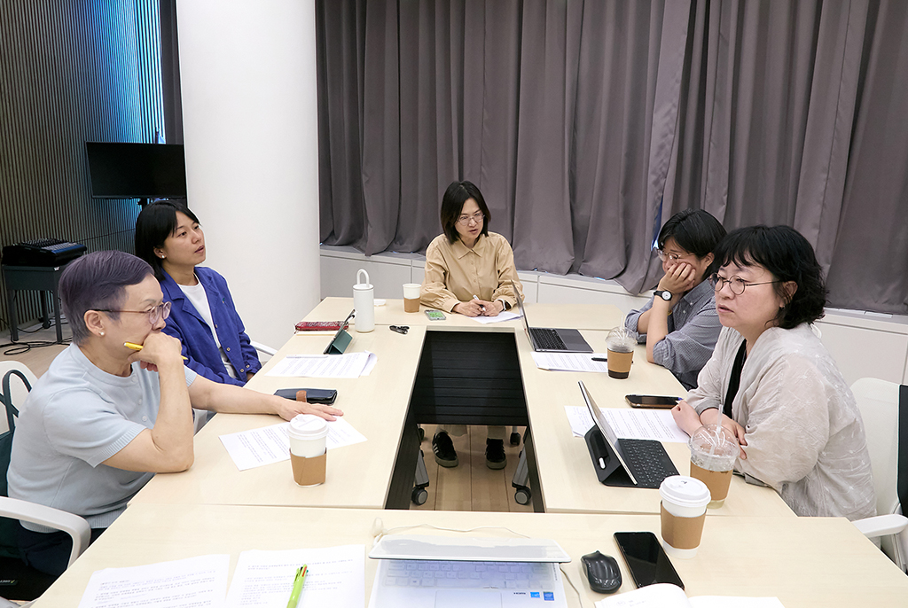 직사각형으로 놓인 테이블을 둘러싸고 마주 앉아 논의를 나누고 있다.