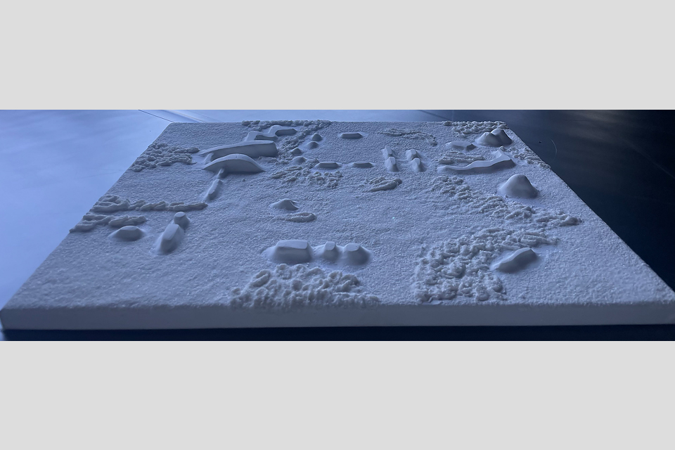 흰색 사각 패널 위에 지점토를 이용해 다양한 크기와 형태의 지형과 건물의 흔적을 입체적으로 표현했다.