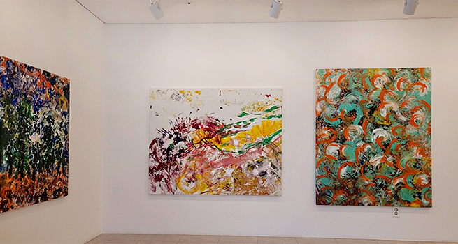 전시장 벽에 추상 회화 세 점이 걸려 있다. 왼쪽은 거친 붓 터치로 숲을 연상시키는 짙은 녹색·주황색 그림, 가운데는 노랑·적색이 뒤섞인 역동적 붓질의 풍경 같은 이미지, 오른쪽은 청록색·주황색 곡선이 반복해서 패턴처럼 구성된 화면이다.