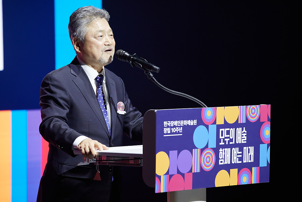 이종열 이사장이 정장 차림에 보라색 넥타이를 매고 단상 앞에 서서 마이크에 대고 발언 중이다.