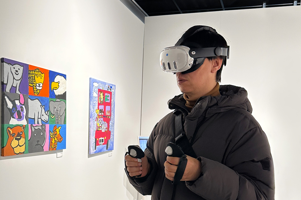 병철이 VR 고글과 컨트롤러를 착용한 채 최석원 작가의 동물을 그린 회화 작품 중 체험형 전시를 즐기고 있다.