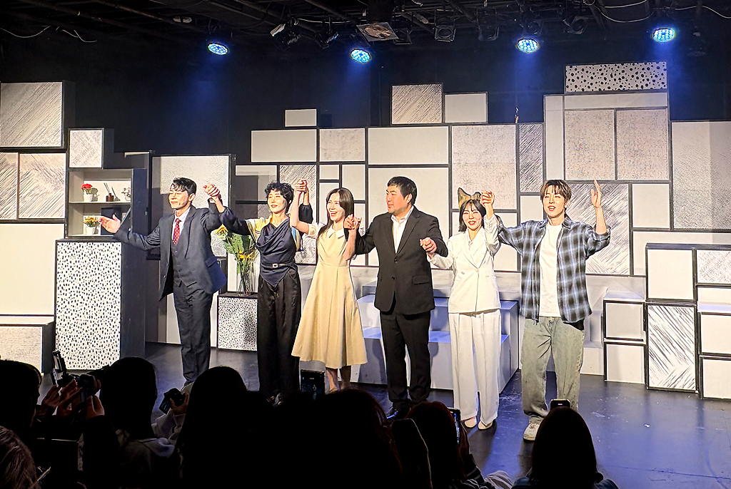 커튼콜. 무대 위에서 여섯 명의 배우가 나란히 서서 맞잡은 손을 들어 올리며 관객을 향해 인사한다. 뒤편에는 무대 소품인 검정색 테두리를 두른 흰색 사각형 박스가 옆으로 위로 겹겹이 놓여 있고, 사이 사이에 꽃병, 화분, 붓 등의 소품이 놓여 있다. 객석에서는 관객들이 박수를 보낸다.