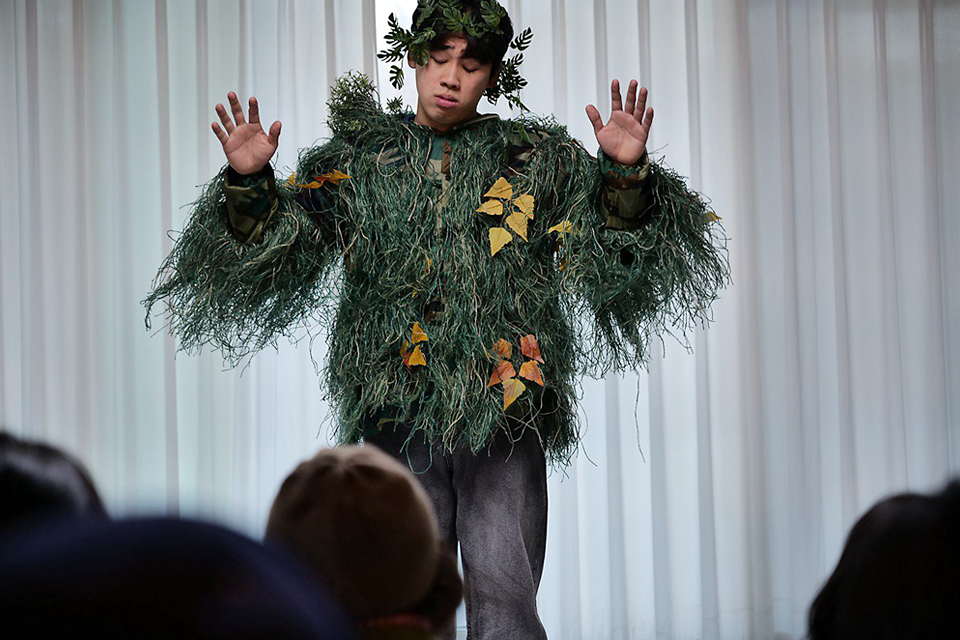 방의 흰색 커튼을 배경으로 관객 앞에서 나뭇잎과 풀로 장식한 의상을 입은 요셉이 나무처럼 두 팔을 위로 들고 두 눈을 감은 채 사색에 잠긴 표정이다.