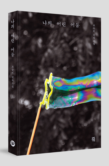 검은색 바탕에 별모양 비눗방울 틀을 통해 알록달록한 비눗방울이 만들어지고 있는 그림의 책표지. 흰글씨로 ‘나의 어린 어둠’과 ‘조승리’라고 쓰여 있다.