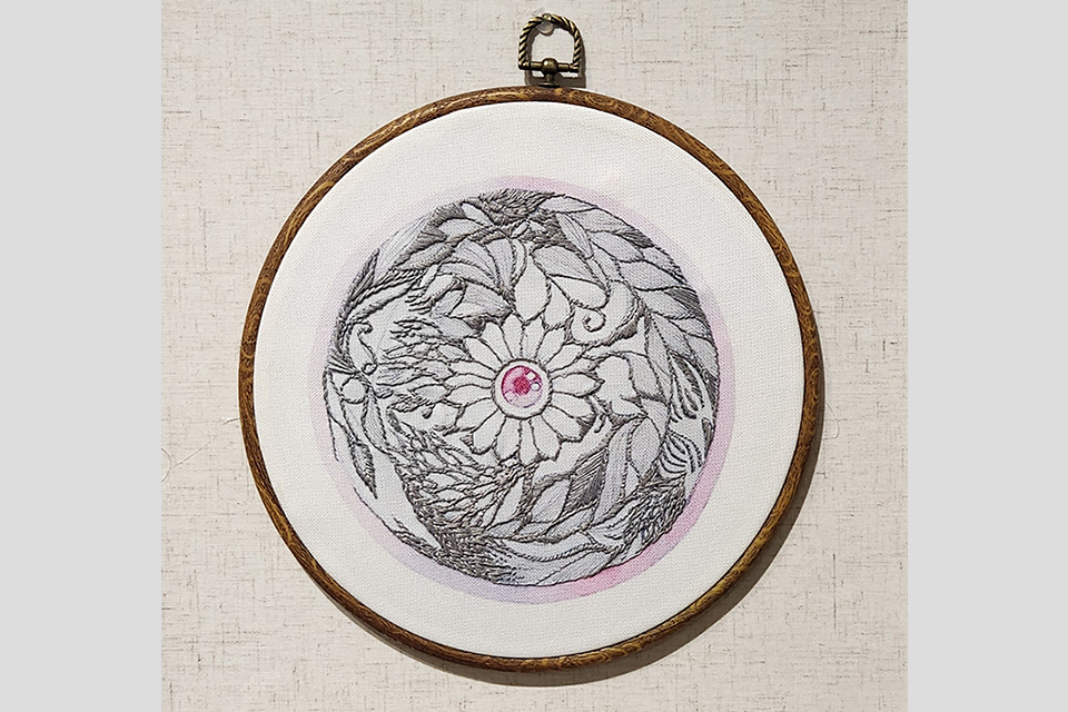 나무로 만든 둥근 수틀에 끼워진 흰 천 위로 회색 실을 사용해 꽃 한 송이와 꽃을 둘러싼 잎사귀 문양을 정교하게 수 놓은 자수 작품이다. 꽃잎 중앙의 꽃술에는 분홍색 실로 눈동자 모양을 수놓았다. 